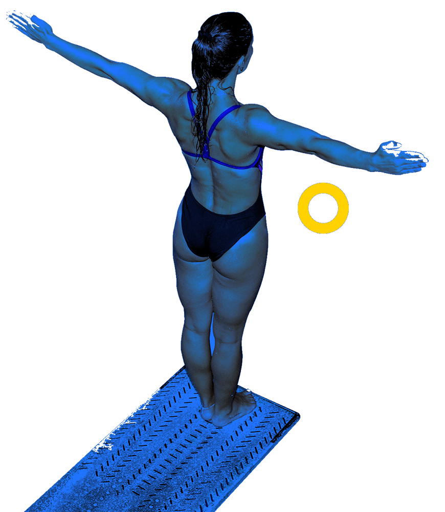 En la foto, una clavadista tiene los brazos extendidos. Se prepara al borde la plataforma para ejecutar su lanzamiento hacia la piscina. 