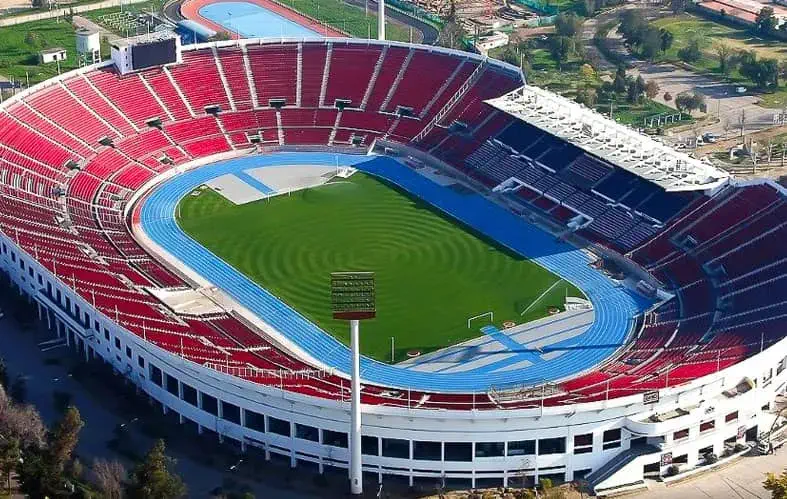 On the image we can see an aerial shot of the
                                    coliseum area of the National Stadium, where you 
                                   can appreciate the professional football court 
                                   surrounded by the athletic track. Also, there is the 
                                   north, south and central area of the stand.